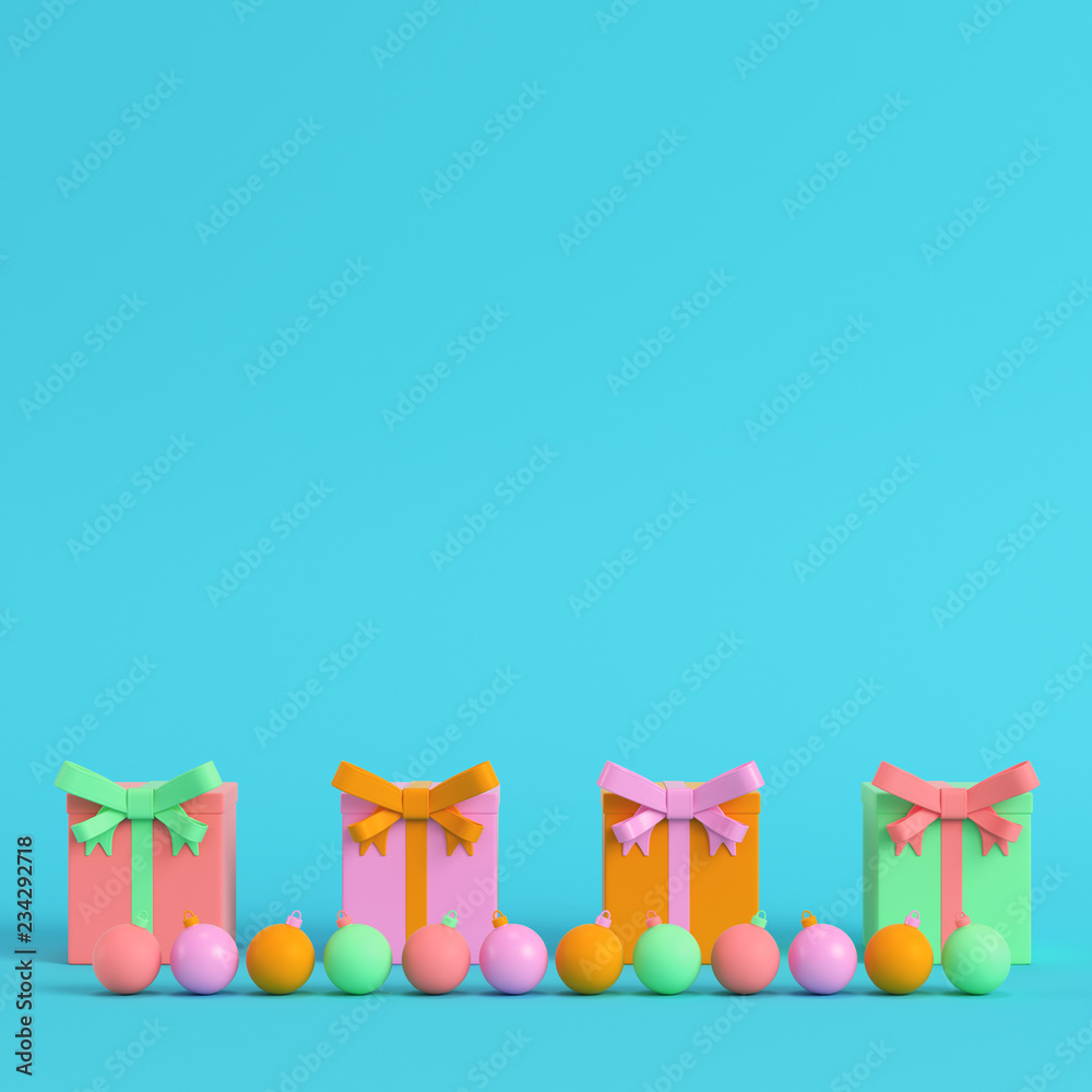 Naklejka premium Four colorful gift boxes with ribbon bow and christmas ball on bright blue background in pastel colors on bright blue background in pastel colors