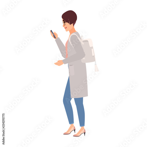 Cute young woman wearing casual clothing, backpack and glasses holding smartphone and texting while walking