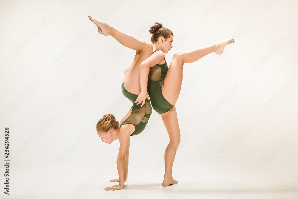 The two modern ballet dancers dancing on gray studio background