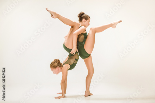 The two modern ballet dancers dancing on gray studio background