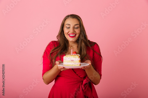 Happy young woman isolated over pink wall background holding cake.