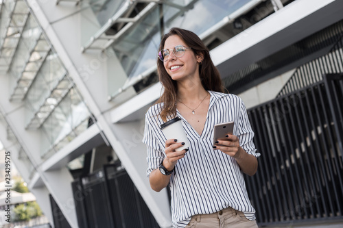 Quadro em tela Cheerful female manager getting to work by foot drinking morning coffee to go wh