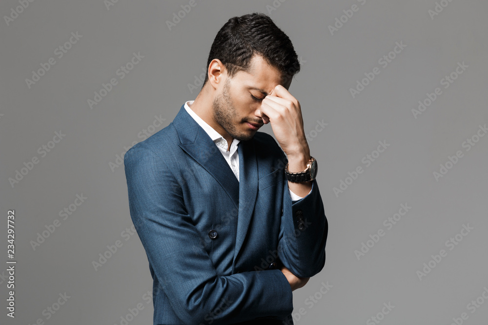 Image of adult arabic businessman 30s in formal suit thinking and touching his face, isolated over gray background Image of adult arabic businessman 30s in formal suit thinking and touching his face, isolated over gray background