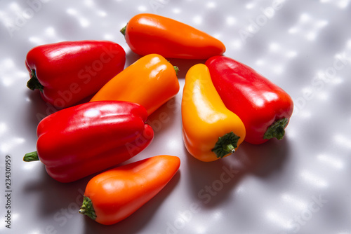 Group of mini paprica, red, yellow and orange on plastic cutting board