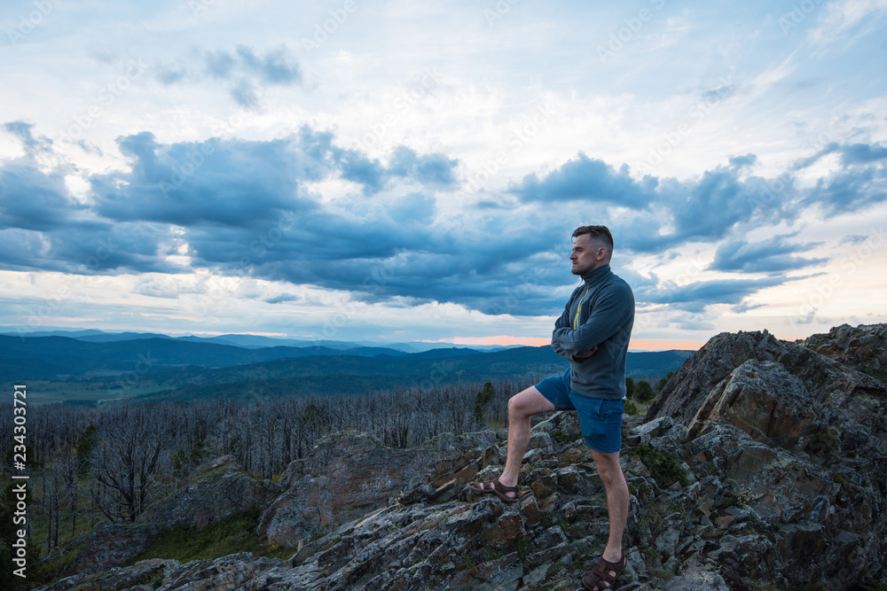 Travel, freedom and tourism concept - man standing on top of cliff in summer beauty evening in Altai mountains