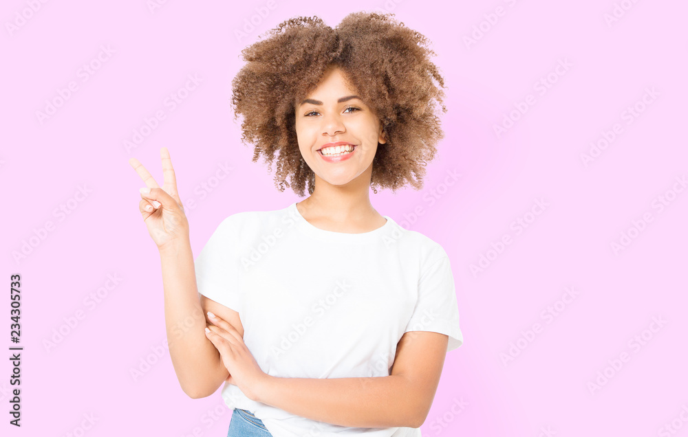 Afro curly hair. Happy young african american girl showing victory sign isolated on pink background. Copy space. Template and blank summer t shirt. Afro curly hair. Happy young african american girl showing victory sign isolated on pink background. Copy space. Template and blank summer t shirt.