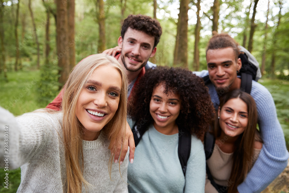 Multi ethnic group of five young adult friends taking a selfie in a forest during a hike, portrait Multi ethnic group of five young adult friends taking a selfie in a forest during a hike, portrait