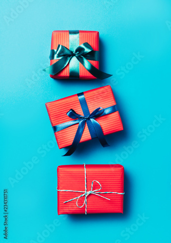 Minimalistic Christmas gift boxes wrapped in red paperon blue frozen background. Bright and festive Christmas concept. Top view, flat lay. Copy spce for text. photo