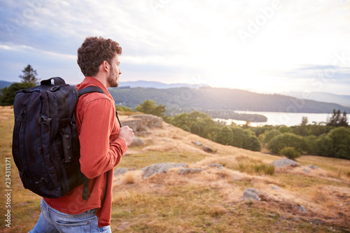 A young adult Caucasian man walking alone on a hill  admiring the view  side view