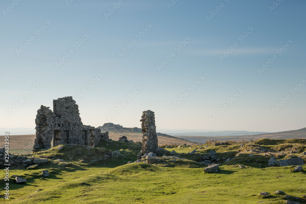 Stunning landscape sunset image over abandoned Foggintor Quarry in Dartmoor with raking soft sunlight over ruins and derelict buildings