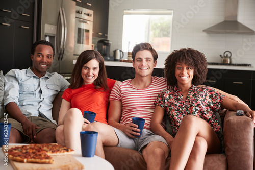Four young adult friends relaxing on couch together at home