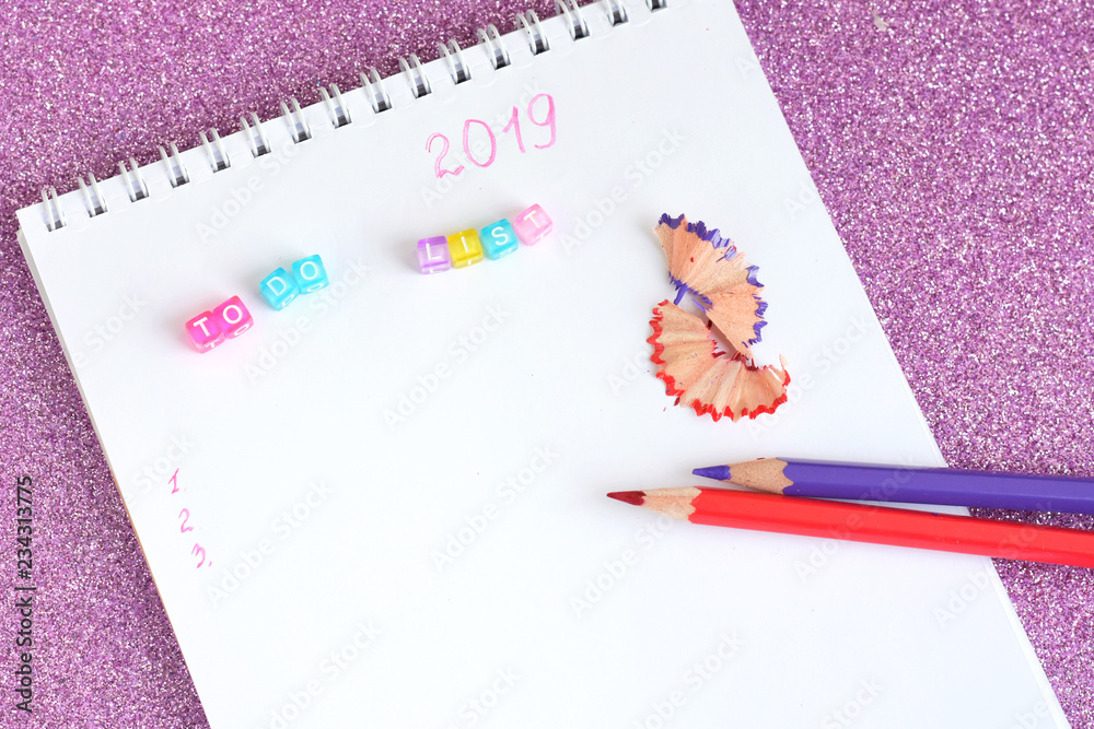 New year 2019 to do list in spiral paper album. Two color pencils red and purple with colorful cute letters and notebook on shiny sparkle violet glittery background. back to school. New year 2019 to do list in spiral paper album. Two color pencils red and purple with colorful cute letters and notebook on shiny sparkle violet glittery background. back to school.