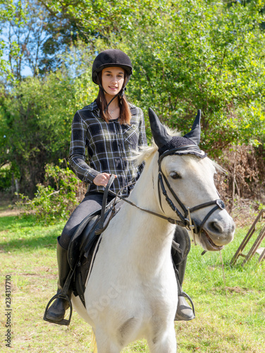 Young woman with black helmet riding white horse © Philipimage