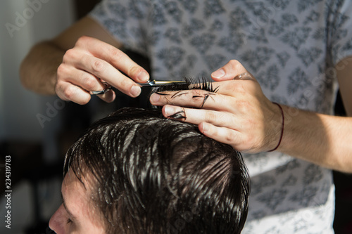 Close up of a haircut at the hair saloon. Barber triming a client's hair with a scissors.