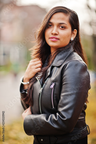 Close up portrait of pretty indian girl in black saree dress and leather jacket posed outdoor at autumn street.