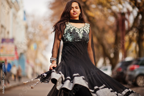 Pretty indian girl in black saree dress posed outdoor at autumn street.