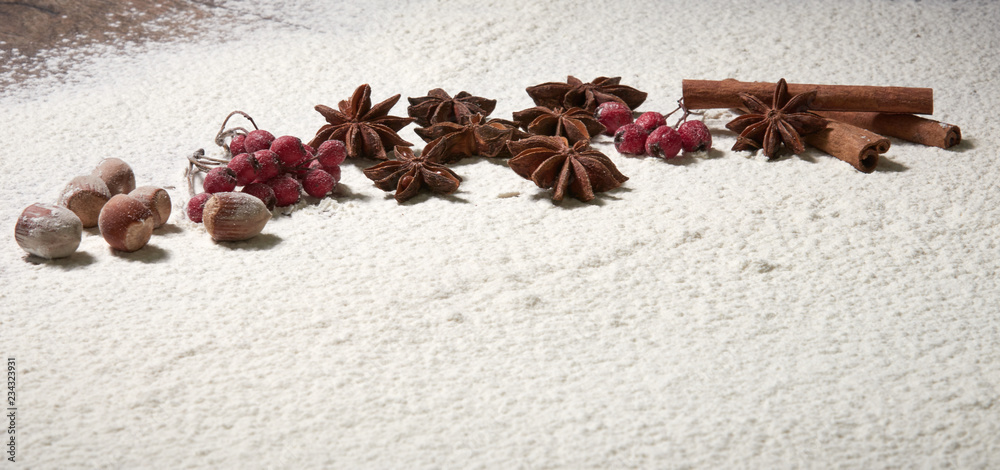 Cinnamon sticks, hazelnuts, star anise stars, red rowan berries on the snow. Winter cooking composition of spices and nuts. Cinnamon sticks, hazelnuts, star anise stars, red rowan berries on the snow. Winter cooking composition of spices and nuts.