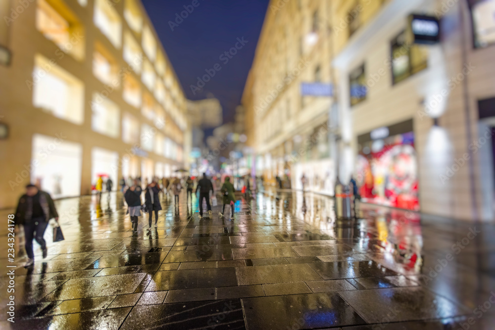 crowd of people walking on the night rainy streets in the city 