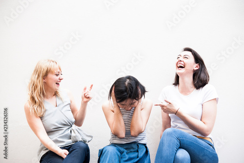 Cupple caucasian women laughing and looking asian woman ,who confused and take their hands off the head, insolvent business ,unsuccessful business concept. photo