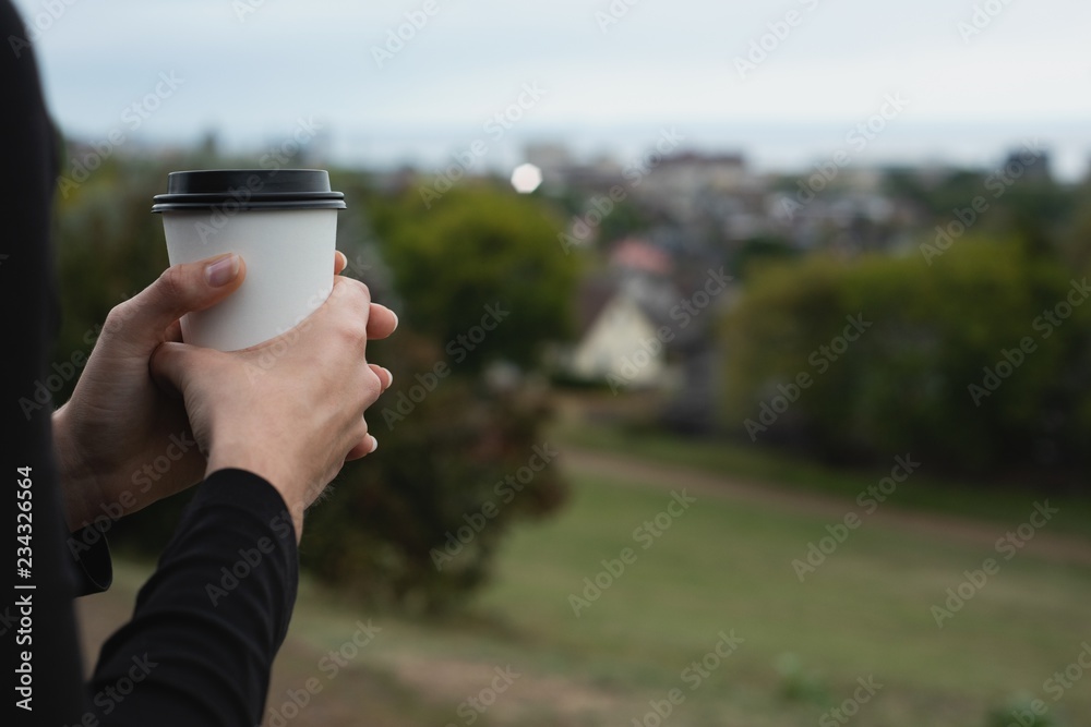 Woman holding coffee cup on a hill Woman holding coffee cup on a hill