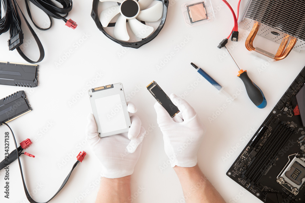 Top view of men holding classic SATA3 SSD and M.2. Computer parts, Electronics repair and upgrade on white desk background, copy space. Motherboard, processor cpu, cooler, radiator, flat lay. Top view of men holding classic SATA3 SSD and M.2. Computer parts, Electronics repair and upgrade on white desk background, copy space. Motherboard, processor cpu, cooler, radiator, flat lay.