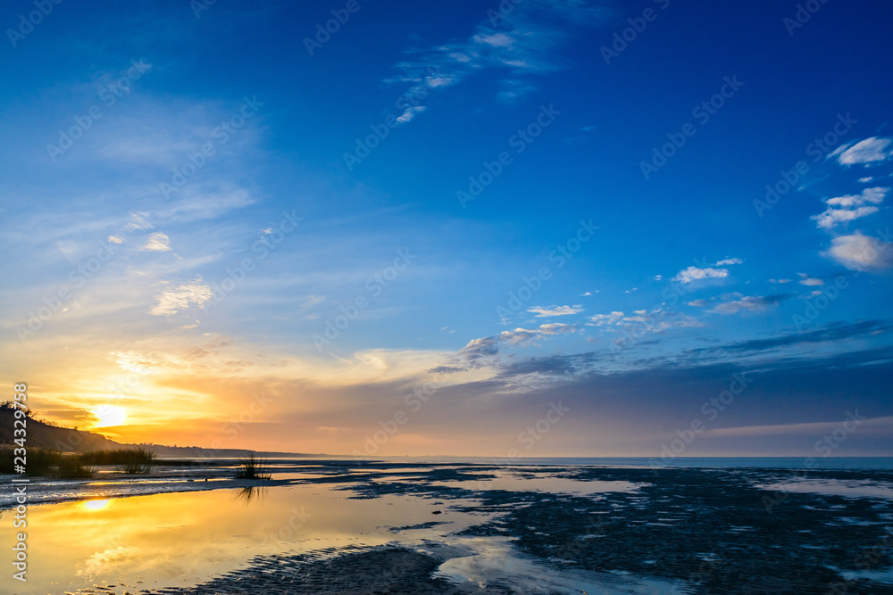 Obraz premium The sea and the beautiful expanse of blue sky with clouds and sunlight at sunset. Russia Azov sea.