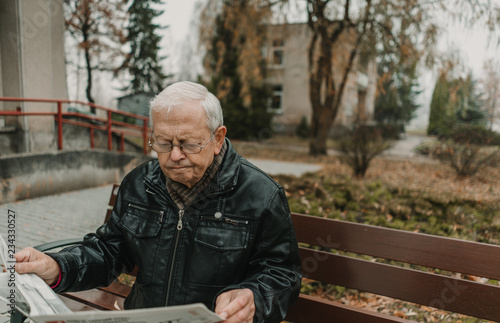 Elderly man reading newspaper in park
