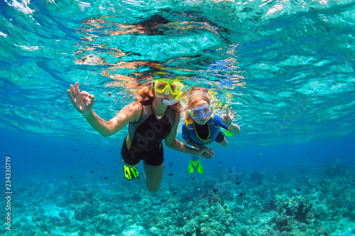 Happy family - mother, kid in snorkeling mask dive underwater with tropical fishes in coral reef sea pool. Show by hands divers sign OK. Travel lifestyle, beach adventure on summer holiday with child. photo