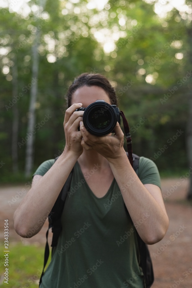 Woman clicking photos with camera in forest Woman clicking photos with camera in forest