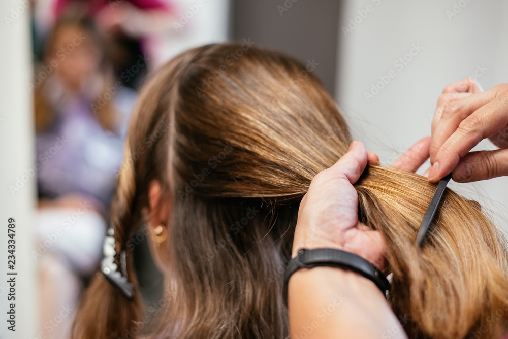 Fototapeta premium Hairdresser combing woman's hair
