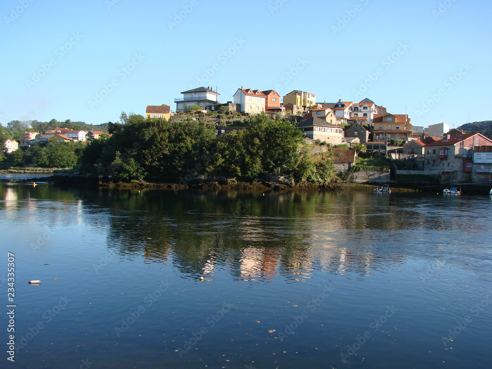 Panorama of the coastal town, which is reflected on the clean surface of the sea gulf, against the blue sky on a sunny day.