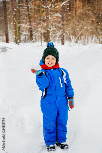 Cheerful child sculpts snowballs outdoors on a winter day.