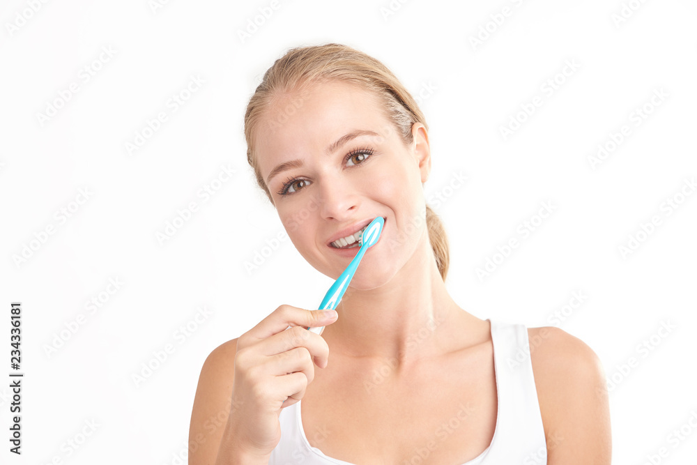 Beautiful young woman brushing her teeth against white background Beautiful young woman brushing her teeth against white background