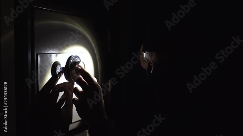 the thief is trying to open the safe in the night