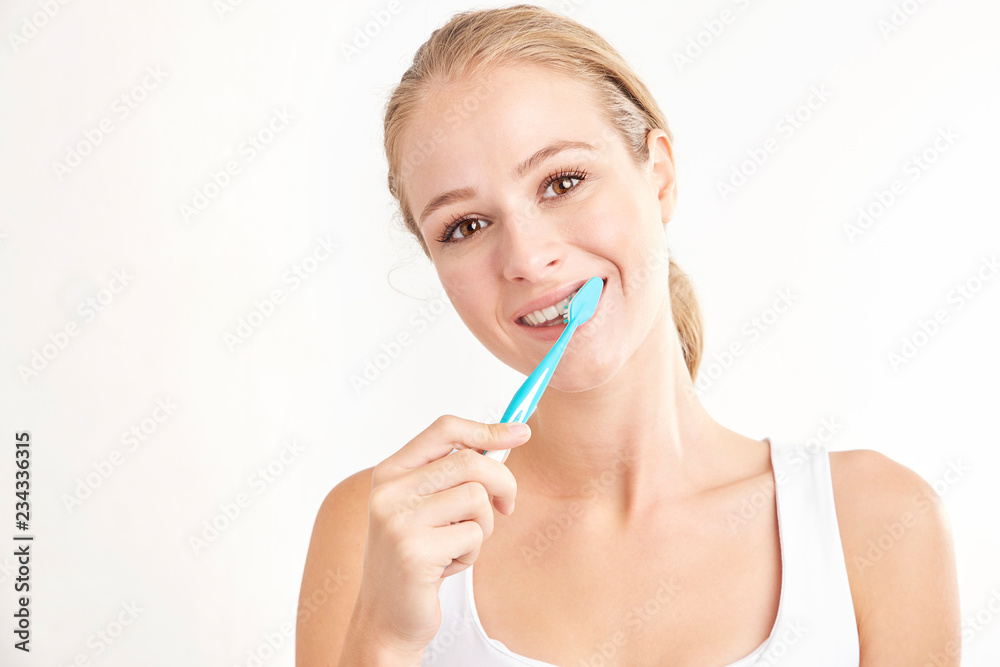 Beautiful young woman brushing her teeth against white background Beautiful young woman brushing her teeth against white background