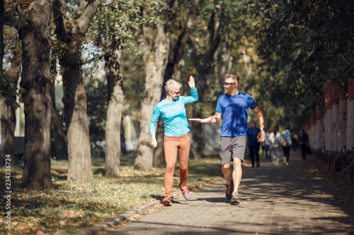 Fototapeta Naklejka Na Ścianę i Meble -  Photo of happy sporting man and woman doing handshake on morning jog