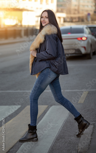 girl in a warm jacket crosses the road