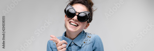 Young brunette girl in black glasses. Cat glasses. The hair is gathered in a bun. Girl dancing. photo