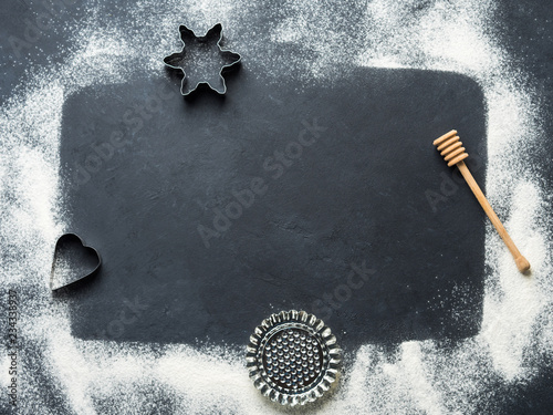 Baking accessories on black background with flour. Christmas winter dark background