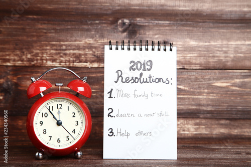 Inscription 2019 resolutions in notepad with red alarm clock
