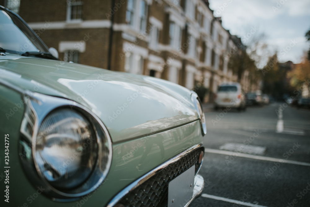 Vintage car headlamp with a classic english street in the background.