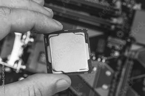 man holding fingers mock up desktop processor 8th gen on background motherboard closeup top view, black and white photo
