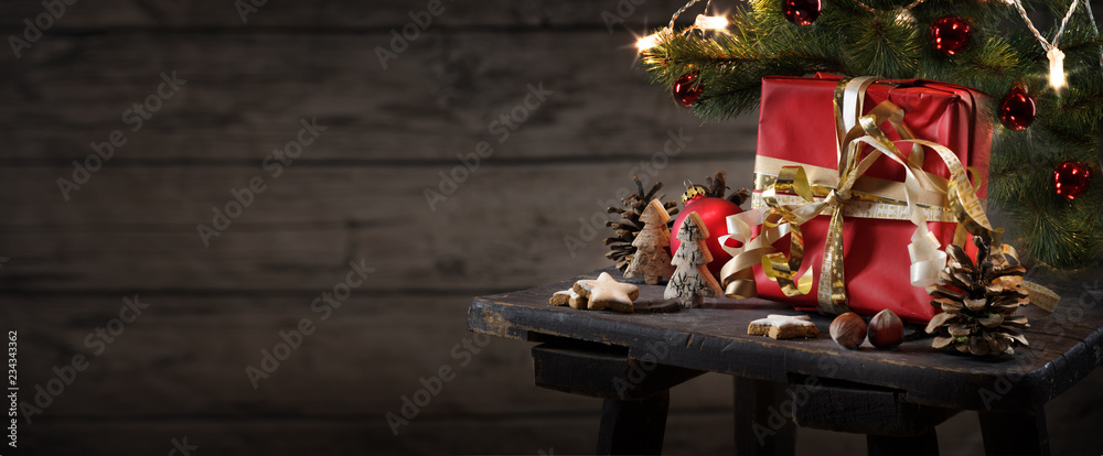 red christmas gift box and decoration on an small table against a rustic wooden wall with copy space, panoramic format red christmas gift box and decoration on an small table against a rustic wooden wall with copy space, panoramic format