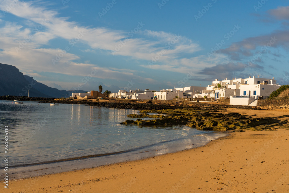 Beautiful empty beach bordered by white houses in Caleta del Sebo on the La Graciosa island, Canary, Spain.