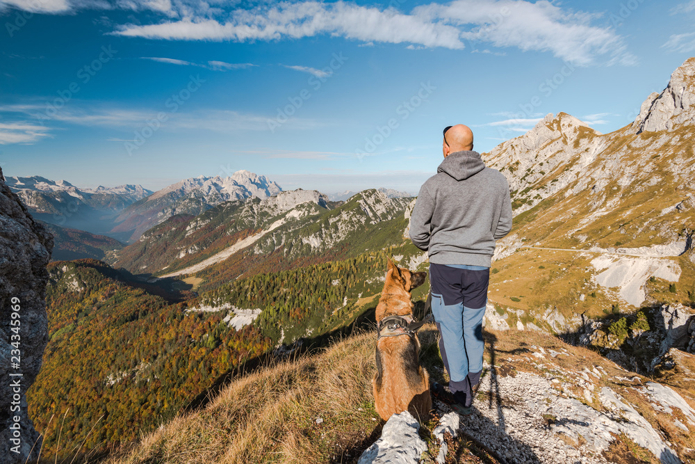Αυτοκόλλητο Man with dog looking at scenic view from high peak