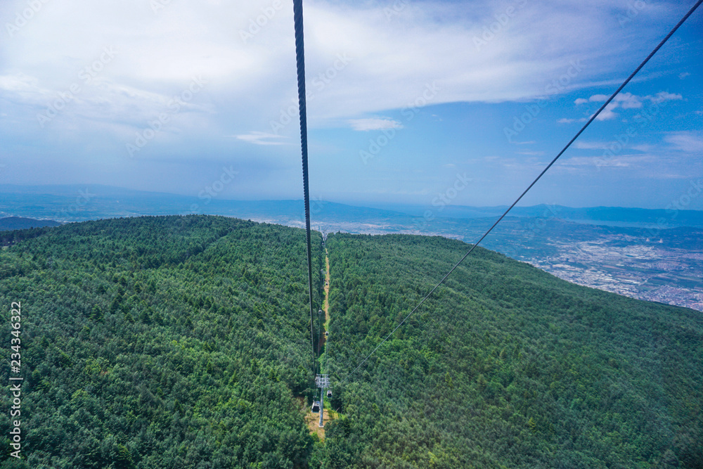 Cable cars going up in to the mountain, green hills