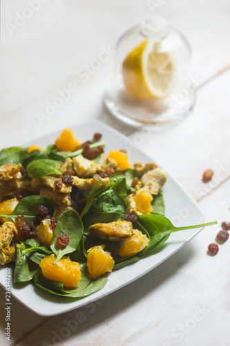 healthy salad with oranges, basil, raisins and honey dressing on white rustic background