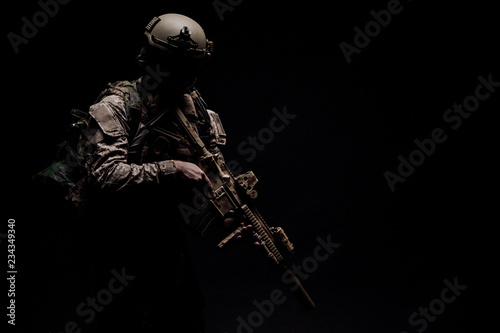 Special forces United States soldier or private military contractor holding rifle. Image on a black background. photo