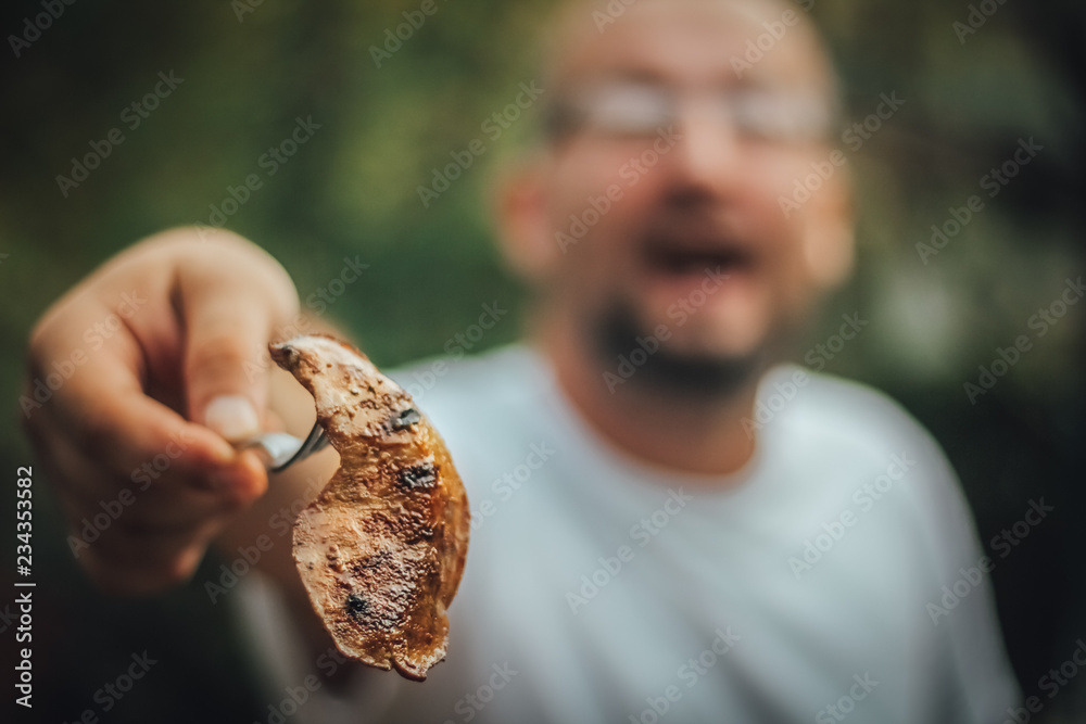 Man with open mouth showing you meat from the grill, outdoor barbecue, copy space Man with open mouth showing you meat from the grill, outdoor barbecue, copy space