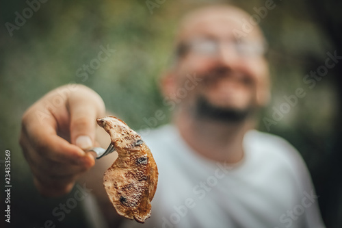 Smiling man showing you meat from the grill, copy space, weekend activities